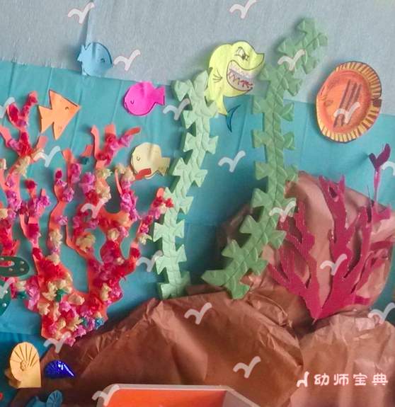 大大的蓝色海洋里有这很多神奇的动物,在小班主题活动大海里的动物中,我们应该充分考虑孩子的年龄特点及发展目标。所以在创设墙饰时可以从以下三点考虑: 1. 师幼共同创设主题墙饰 大海里的动物 用皱纹纸设计了一个蔚蓝色的大海背景,并用三层不同颜色分为深海与浅海及海面。 大海中的各种各样的海洋动物都是鼓励孩子和家长共同制作的亲子作品及孩子的美工区作品,还有孩子搜集到个各种海洋动物模型、毛绒玩具。 在主题活动过程中,我们依次将海洋中的动物装饰到背景中,例如螃蟹、小虾、海星等都在海底的沙石层